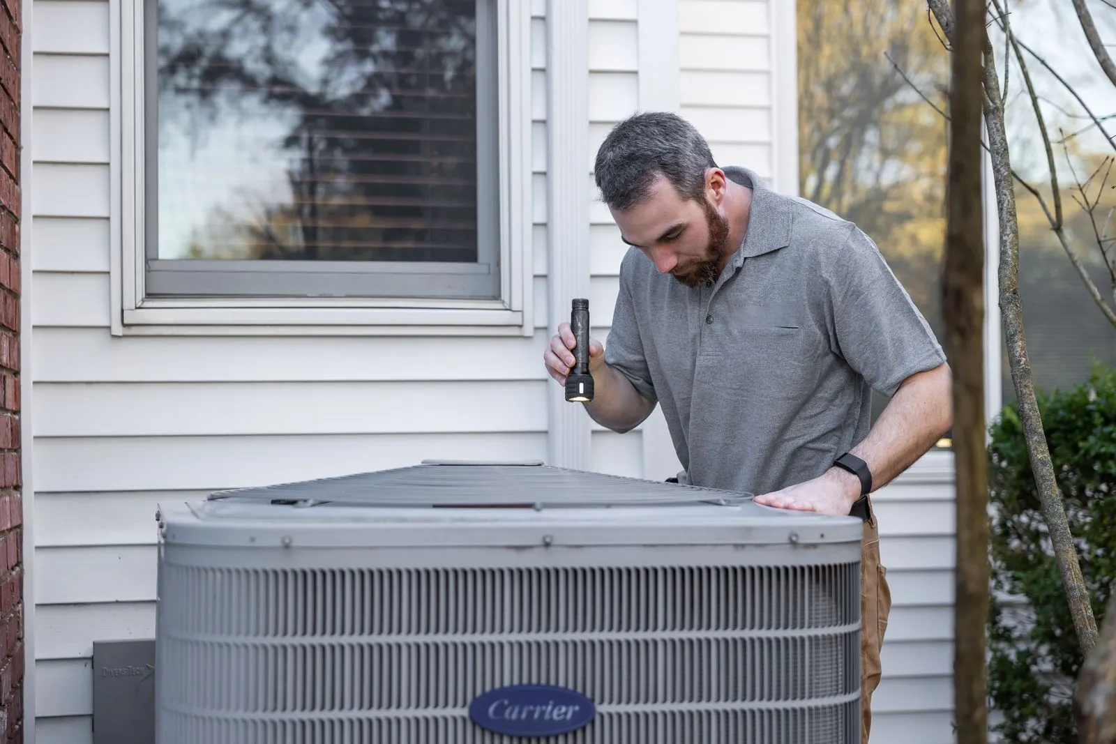 A Kessler technician inspecting an outdoor condensing unit